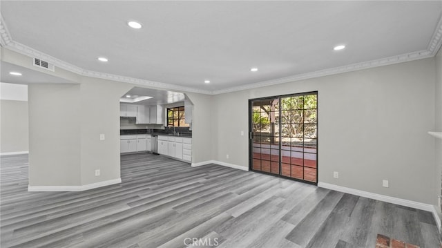 unfurnished living room featuring light hardwood / wood-style floors and crown molding