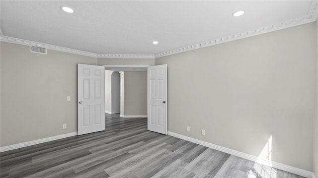 empty room with ornamental molding and hardwood / wood-style flooring