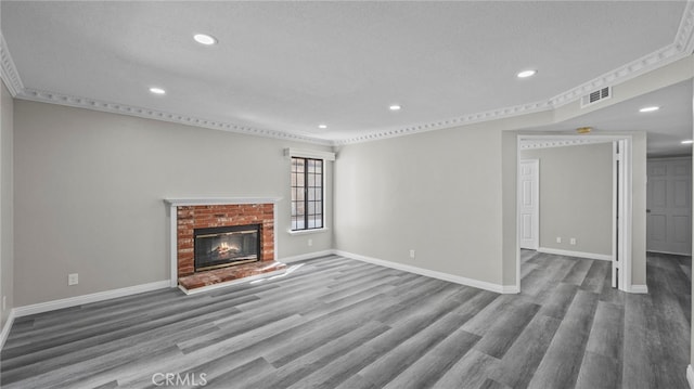 unfurnished living room with wood-type flooring, a textured ceiling, and a brick fireplace