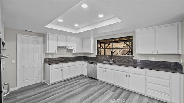 kitchen with dishwasher, a raised ceiling, white cabinetry, and sink