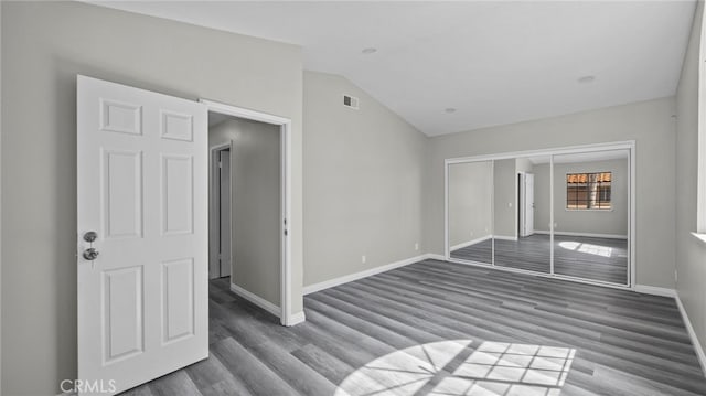 unfurnished bedroom featuring lofted ceiling, dark wood-type flooring, and a closet