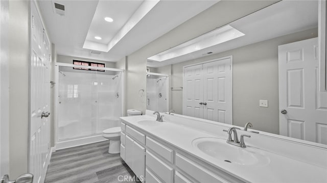 bathroom featuring hardwood / wood-style floors, vanity, a shower with shower door, and toilet