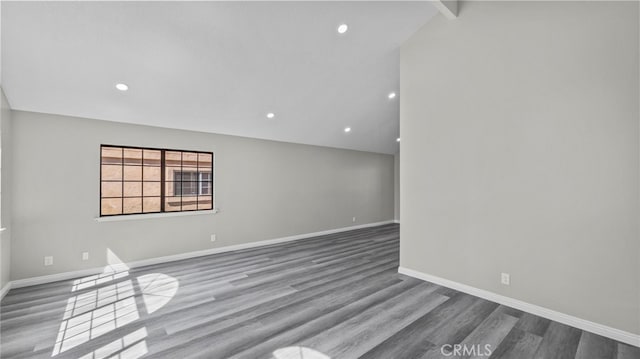 unfurnished room featuring vaulted ceiling with beams and hardwood / wood-style flooring