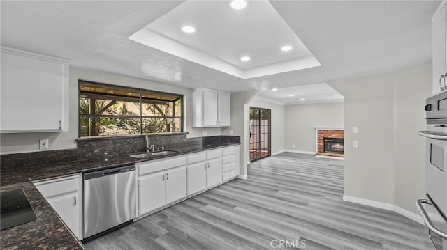 kitchen featuring dishwasher, white cabinets, a raised ceiling, and light hardwood / wood-style floors