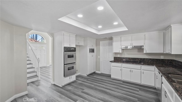 kitchen with white cabinets, stainless steel appliances, and dark stone counters