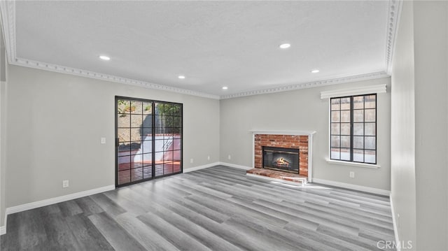 unfurnished living room featuring a textured ceiling, light wood-type flooring, crown molding, and a brick fireplace