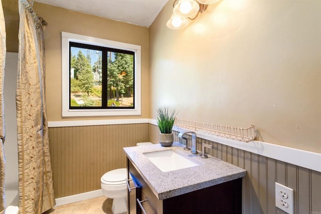 bathroom featuring tile patterned floors, toilet, vanity, wooden walls, and curtained shower