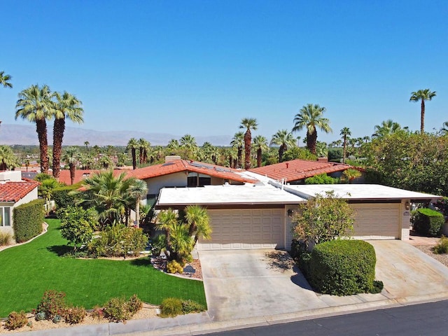 view of front of property with a front yard, a mountain view, and a garage