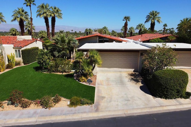 view of front of property with a mountain view, a front lawn, and a garage