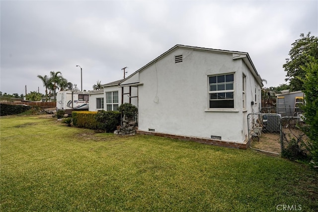 view of property exterior with a lawn and central AC