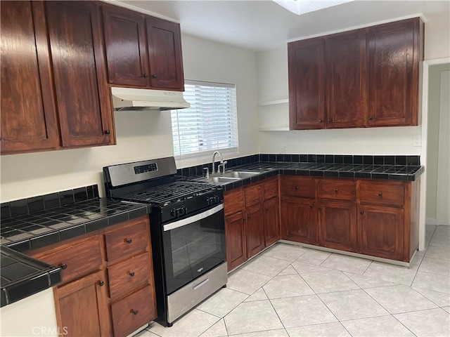 kitchen featuring gas stove, light tile patterned floors, and sink