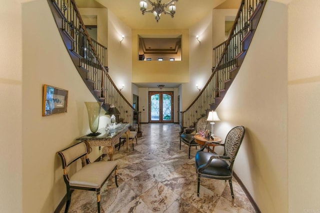 foyer entrance with french doors, a towering ceiling, and a chandelier