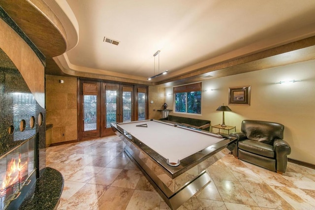 rec room with pool table, a raised ceiling, french doors, and a fireplace