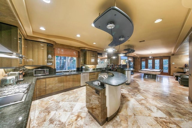 kitchen with stainless steel appliances, pendant lighting, dark stone counters, and billiards