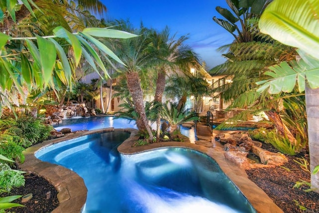 pool at dusk with an in ground hot tub