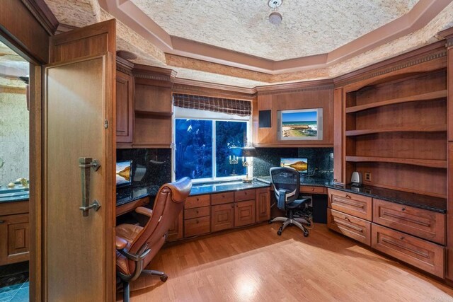 home office with built in desk and light wood-type flooring