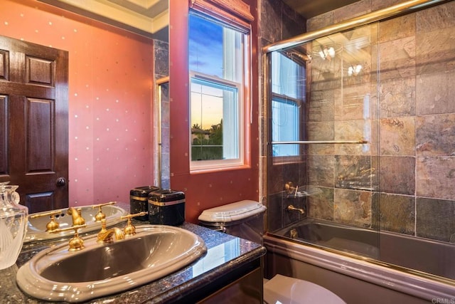 full bathroom featuring toilet, bath / shower combo with glass door, and sink