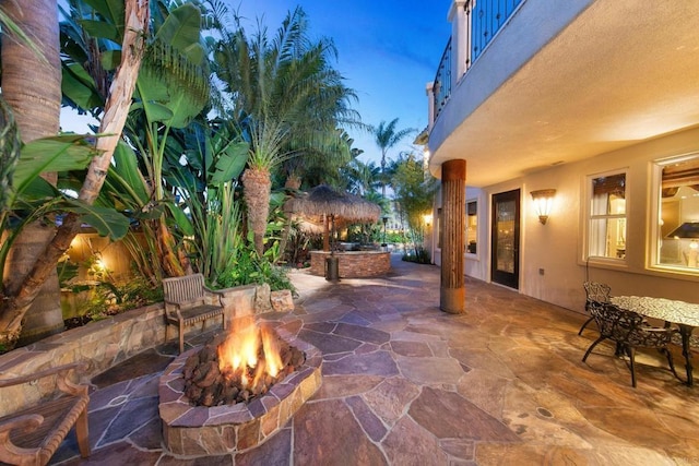 patio terrace at dusk with a balcony and an outdoor fire pit