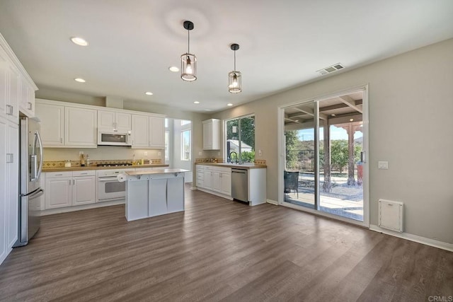 kitchen with hanging light fixtures, stainless steel appliances, a center island, and white cabinets