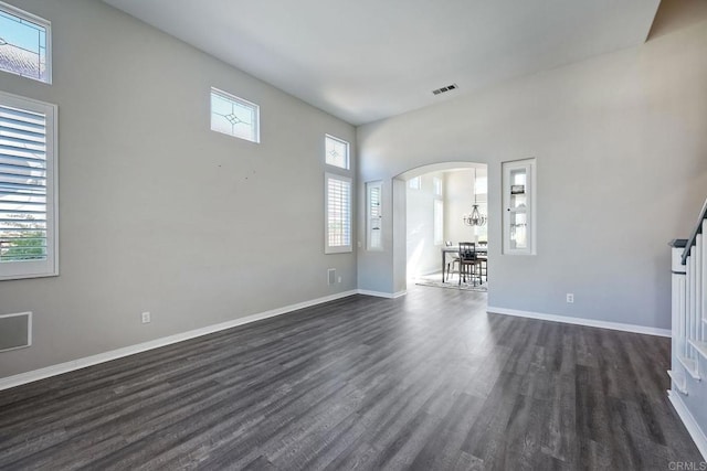 unfurnished living room with dark hardwood / wood-style flooring and a towering ceiling