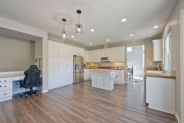 kitchen with sink, white cabinetry, stainless steel fridge with ice dispenser, a kitchen island, and pendant lighting