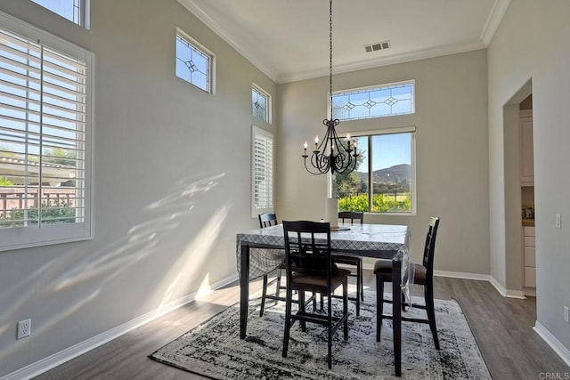 dining room with crown molding, dark hardwood / wood-style floors, a wealth of natural light, and a notable chandelier