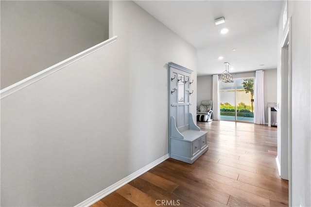 corridor featuring hardwood / wood-style flooring and an inviting chandelier