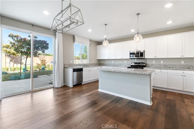 kitchen featuring light stone counters, stainless steel appliances, decorative light fixtures, white cabinets, and dark hardwood / wood-style floors