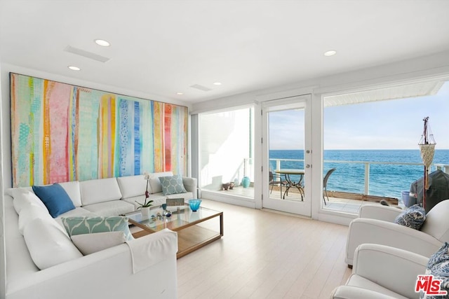 living room featuring light wood-type flooring and a water view