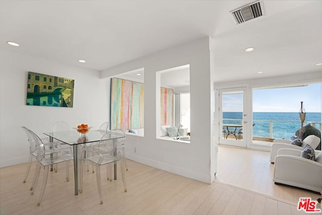 dining area featuring light hardwood / wood-style floors and a water view