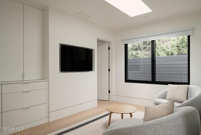 living room featuring light wood-type flooring and a skylight