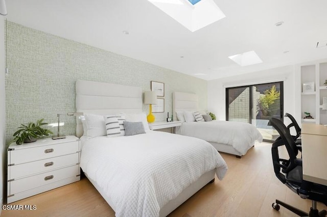 bedroom featuring light wood-type flooring, a skylight, and access to exterior