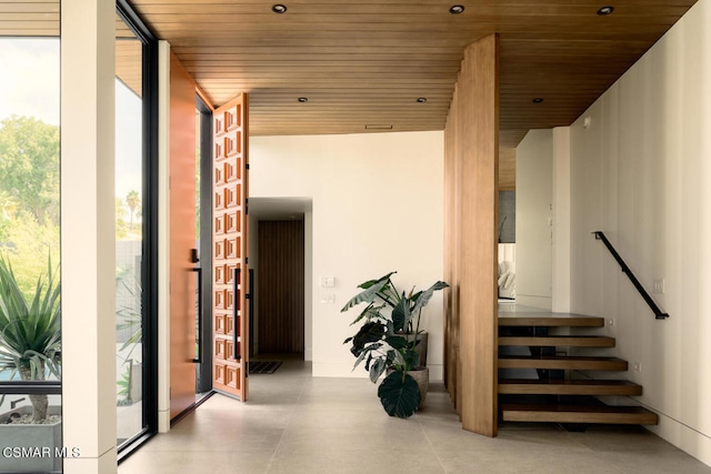 stairway with concrete floors, wooden ceiling, and expansive windows