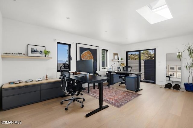 office area with light wood-type flooring and a skylight