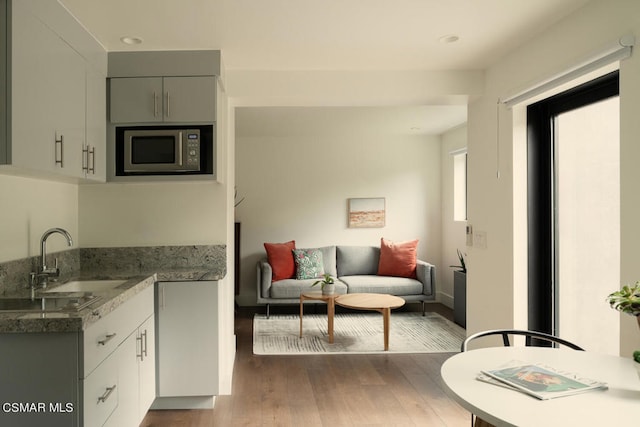 kitchen featuring dark hardwood / wood-style floors, stainless steel microwave, sink, and gray cabinets