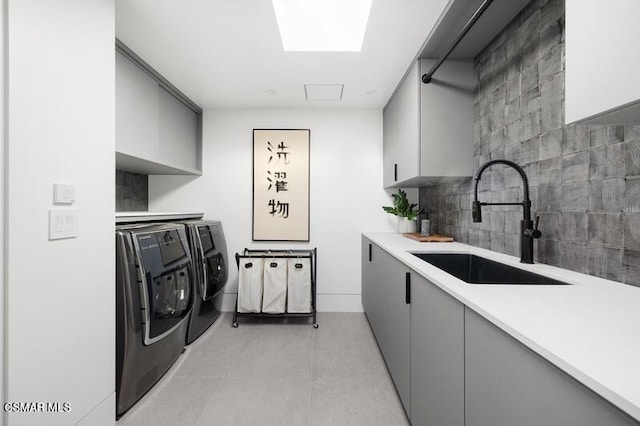 clothes washing area with cabinets, a skylight, sink, and independent washer and dryer