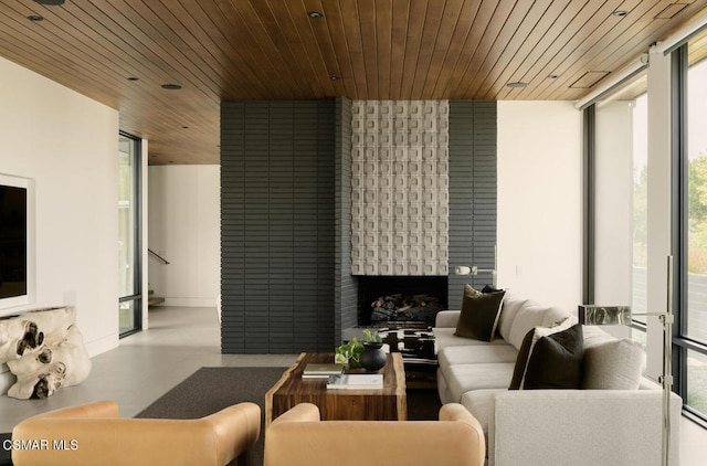 living room featuring a wall of windows, a fireplace, and wooden ceiling