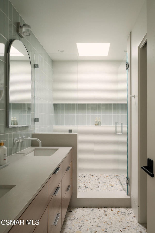 bathroom with a shower, vanity, tile walls, and a skylight