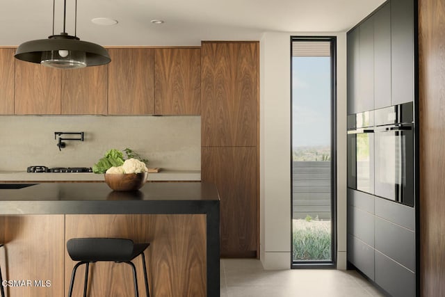 kitchen with a kitchen breakfast bar, gas cooktop, and decorative light fixtures