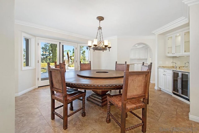 dining space featuring wine cooler, ornamental molding, an inviting chandelier, and indoor bar