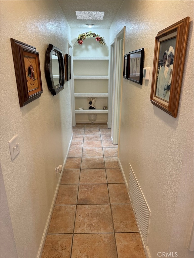 hall with light tile patterned flooring and a textured ceiling