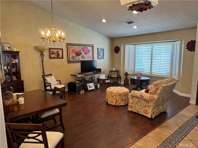 living room featuring a notable chandelier, lofted ceiling, hardwood / wood-style floors, and a textured ceiling