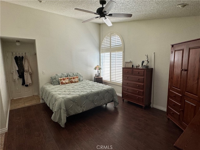 bedroom featuring ceiling fan, dark wood-type flooring, and a textured ceiling