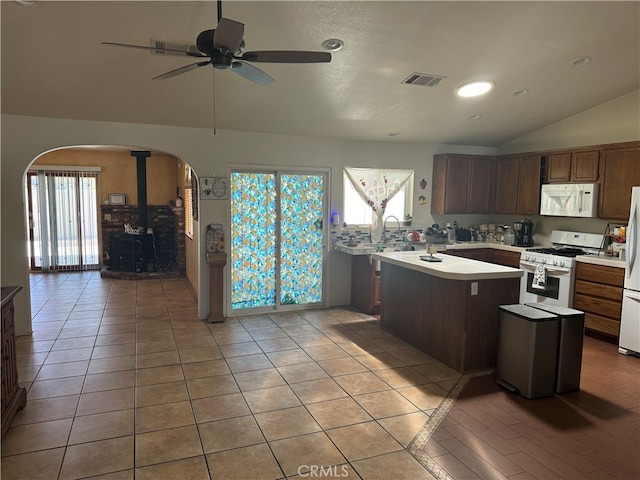 kitchen with a center island, lofted ceiling, white appliances, light tile patterned floors, and ceiling fan