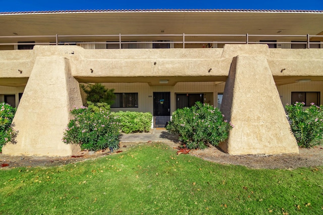 rear view of property with a lawn and a balcony