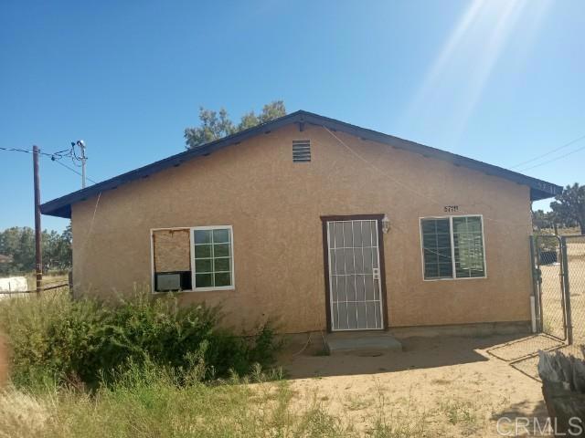 rear view of house featuring stucco siding and fence