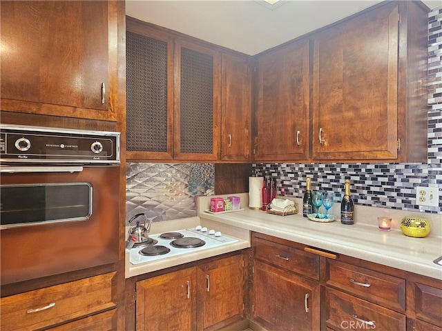 kitchen featuring decorative backsplash, white electric stovetop, and black oven