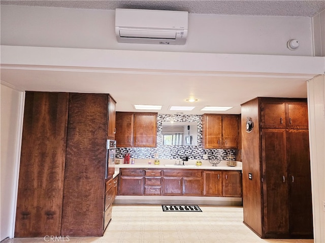 kitchen with stainless steel oven, sink, a wall unit AC, and tasteful backsplash