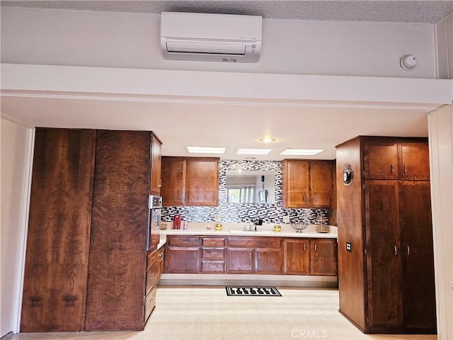 kitchen with light countertops, light floors, a wall mounted AC, and brown cabinetry