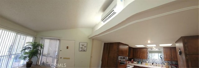 kitchen featuring decorative backsplash, vaulted ceiling, wall oven, and a wealth of natural light